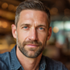 Caucasian man with short hair and trimmed beard, soft warm lighting and a clean background.